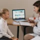 Doutora psicopedagógica interage com uma menina em consulta, diante de um computador durante uma intervenção cognitiva.