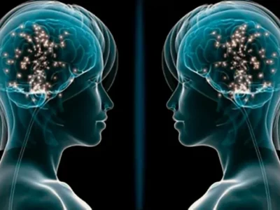 Duas silhuetas humanas de perfil, frente a frente, com cérebros brilhantes e faíscas de conexões, sobre fundo preto.