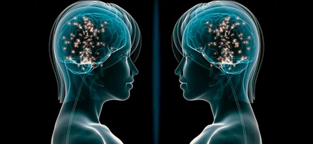 Duas silhuetas humanas de perfil frente a frente, com cérebros brilhantes e faíscas de conexões neuronais, sobre fundo preto.
