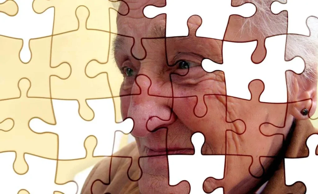 Rosto de uma pessoa idosa parcialmente coberto por peças transparentes de um quebra-cabeça, simbolizando a percepção visual no Alzheimer.