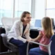 O pediatra conversa com uma criança em um consultório; bata branca e ambiente clínico que transmite atenção infantojuvenil.