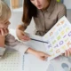 Sessão de fonoaudiologia em consultório clínico: o fonoaudiólogo com uma criança trabalhando com cartões de letras coloridos na mesa.
