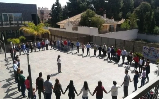 Grupo de pessoas com síndrome de Down formando um círculo ao ar livre, participando de uma dinâmica guiada por uma facilitadora.
