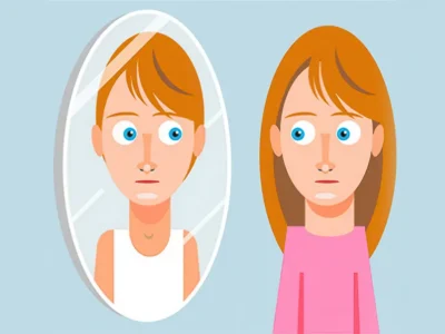 Mulher de cabelo castanho claro ao lado de um espelho; o reflexo veste uma camiseta branca e a figura à direita usa camiseta rosa, sobre um fundo azul.