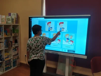 Criança sentada em frente a um tablet, realizando exercícios de cognição social com o NeuronUP, supervisionada por um profissional.