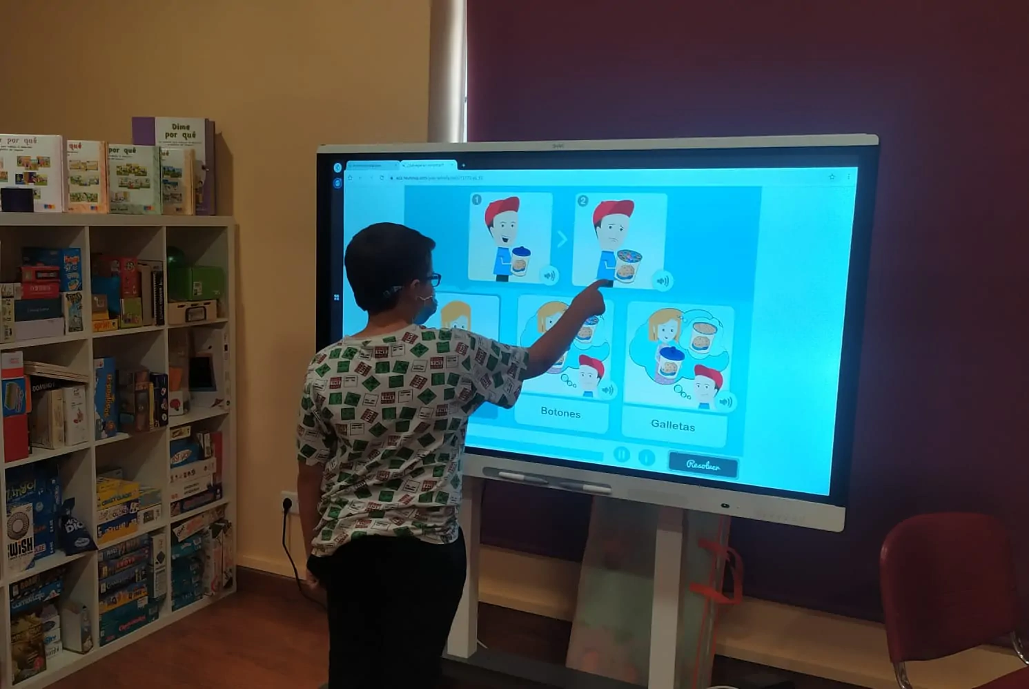 Criança sentada em frente a um tablet, realizando exercícios de cognição social com NeuronUP, supervisionada por um profissional.