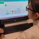 Profissional de neuropsicologia sentado diante de um computador em um ambiente clínico, usando NeuronUP para estimulação cognitiva (caso UNIR).