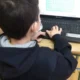 Aluno em sala de aula, sentado diante de um notebook com máscara, concentrado em um labirinto na tela para estimulação cognitiva com o NeuronUP.