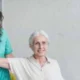 Fisioterapeuta orienta uma pessoa idosa durante a reabilitação em uma clínica, destacando o exercício terapêutico e o apoio ao paciente.