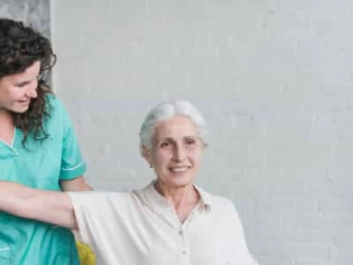 Fisioterapeuta orienta uma pessoa idosa durante a reabilitação em uma clínica, destacando o exercício terapêutico e o apoio ao paciente.