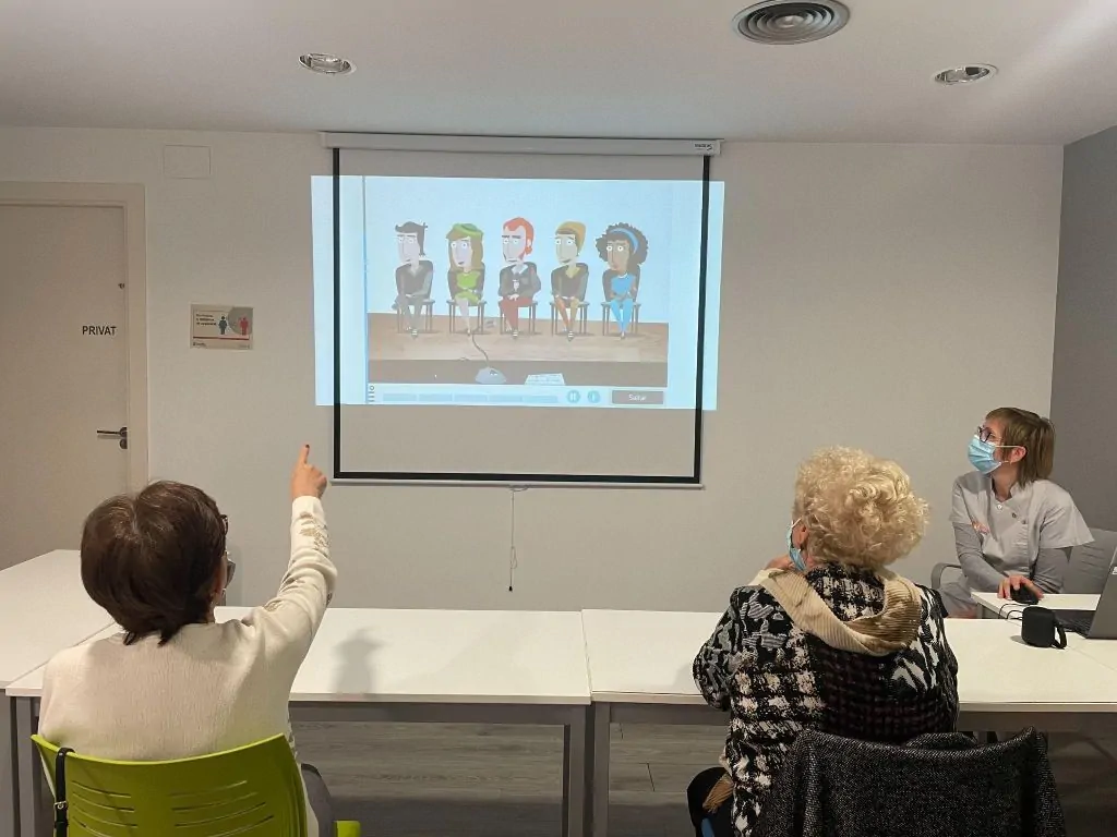 Grupo de profissionais em uma sala de reuniões discutindo reabilitação neuropsicológica, com uma pessoa em pé em frente a uma tela.
