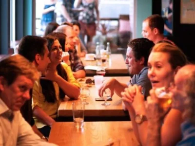 Grupo diverso de pessoas sorrindo e conversando em um ambiente acolhedor tipo café, uma atividade de habilidades sociais.