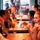 Grupo diverso de pessoas sorrindo e conversando em um ambiente acolhedor tipo café, uma atividade de habilidades sociais.