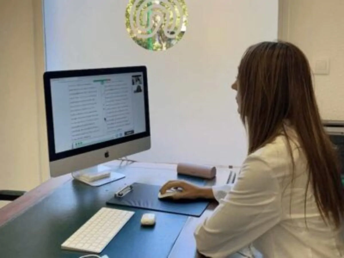 Mulher neuropsicóloga diante de uma mesa observa a tela com exercícios do NeuronUP em um ambiente clínico do IENSA.