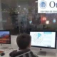 Criança em frente a um computador com dois monitores, um com gráfico circular; fundo com Otaduy Centro de Educação e Saúde.