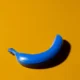 Banana azul pintada sobre um fundo amarelo, criando um contraste visual chamativo e um toque surrealista na diapositiva.