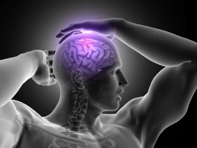 Figura de uma silhueta humana clara segurando a cabeça; dentro do crânio, um cérebro roxo brilhante, fundo escuro.