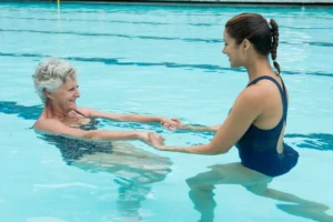 Terapia ocupacional em meio aquático, mulher idosa treinando com pesos na piscina
