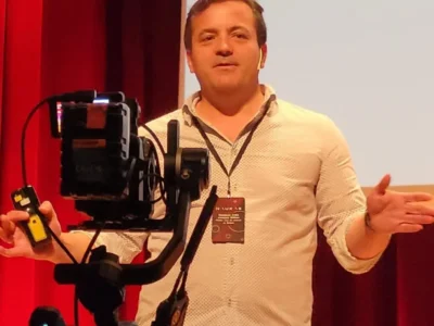 Fotografia de Jesús M. Cortes em uma intervenção pública, com microfone e tela; ilustra a entrevista sobre a previsão da deterioração cognitiva com NeuronUP.