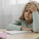 Menina em sala de aula, com caderno e materiais, expressão de concentração e frustração; foco no TDAH e na função executiva.