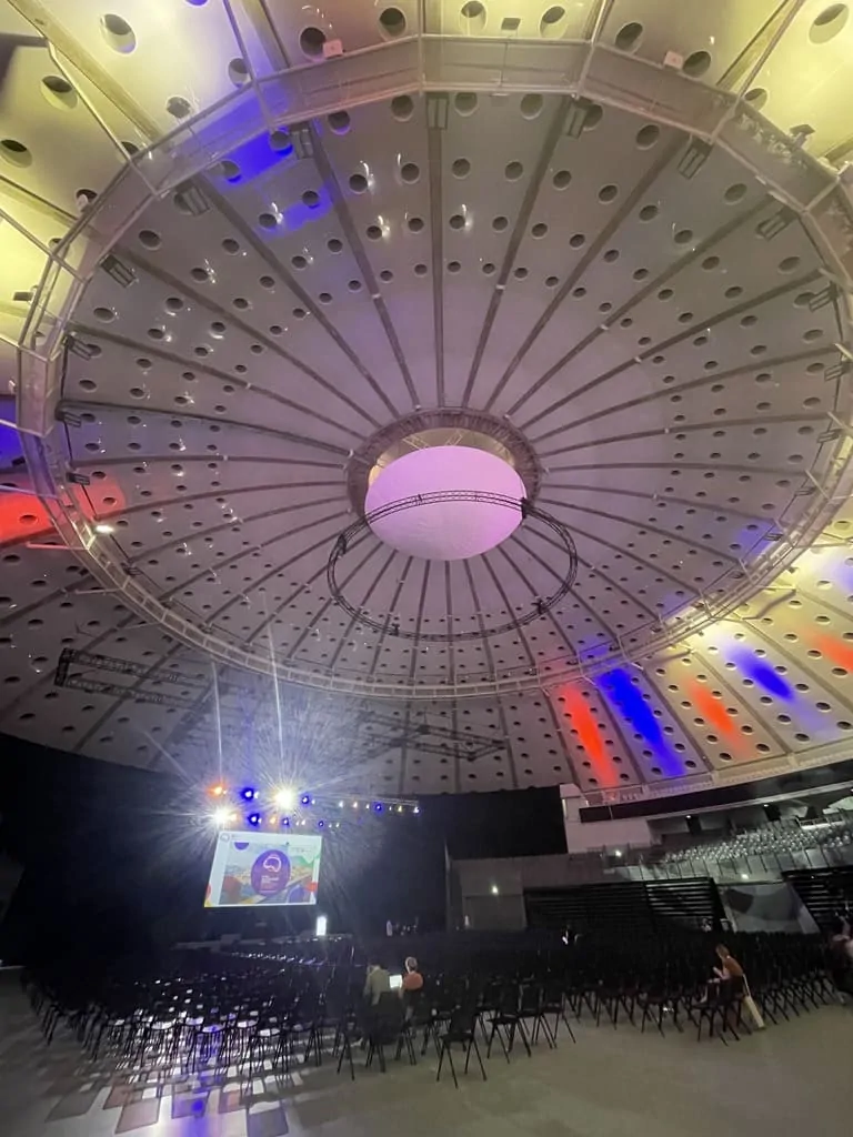 Interior de um auditório no Global Neuropsychology Congress em Porto, palco iluminado e público diverso atento.