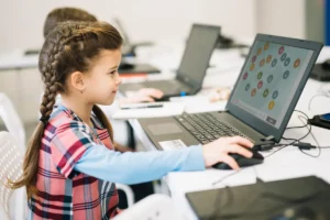 Menina frente a um portátil em uma sala de aula, explorando atividades do NeuronUP na tela para trabalhar memória de trabalho e alfabetização.