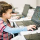 Menina em frente a um notebook em uma sala de aula, explorando atividades do NeuronUP na tela para trabalhar memória e alfabetização.