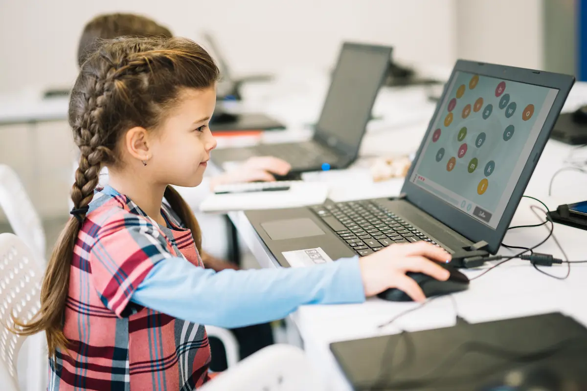 Menina frente a um portátil em uma sala de aula, explorando atividades do NeuronUP na tela para trabalhar memória de trabalho e alfabetização.