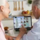 Casal de idosos diante de um notebook com NeuronUP2Go, realizando intervenção cognitiva, com xícara e pãozinho na mesa.