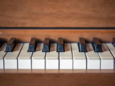 Teclas de piano brancas e pretas sobre fundo de madeira, associado a um programa de acessibilidade musical para reabilitação.