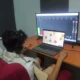 Pessoa concentrada diante de um computador e de uma tela com dados, fones de ouvido, durante reabilitação cognitiva BIQAF.