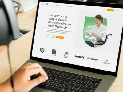 Um menor interagindo com um portátil em um ambiente terapêutico, com a página da NeuronUP e logotipos institucionais visíveis.
