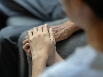 Mãos entrelaçadas de uma pessoa idosa e outra mais jovem, simbolizando apoio na reabilitação cerebral.