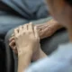 Mãos entrelaçadas de uma pessoa idosa e outra mais jovem, simbolizando apoio na reabilitação cerebral.