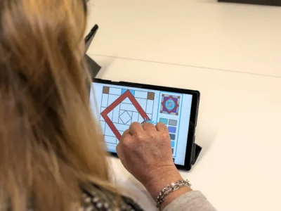 Pessoa de costas usa um tablet durante a estimulação cognitiva com a NeuronUP em Elkarkide Iturrama, diante de uma mesa.