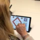 Pessoa de costas usa um tablet durante a estimulação cognitiva com a NeuronUP em Elkarkide Iturrama, diante de uma mesa.