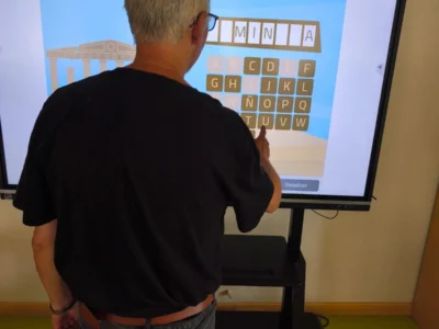 Pessoa de costas interagindo com uma tela exibindo letras para estimulação cognitiva com NeuronUP em Espartales.