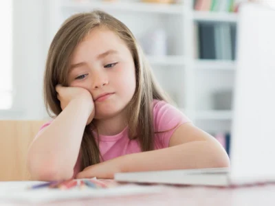 Menina diante do notebook, com a mão no queixo, ilustrando transtornos do neurodesenvolvimento sob uma perspectiva de gênero.