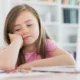 Menina diante do notebook, com a mão no queixo, ilustrando transtornos do neurodesenvolvimento sob uma perspectiva de gênero.