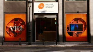 Fachada da VIU com janelas modernas e logotipo branco sobre fundo laranja, entrada de vidro.