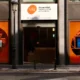 Fachada da VIU com janelas modernas e logotipo branco sobre fundo laranja, entrada de vidro.