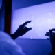 Pessoa diante de uma tela holográfica azul que mostra um rosto esquemático, simbolizando IA em neurociência e estimulação cognitiva.