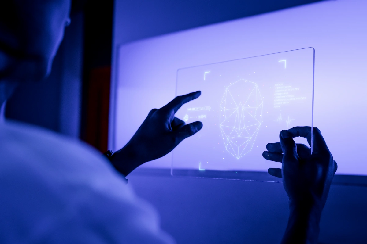 Pessoa diante de uma tela holográfica azul que mostra um rosto esquemático, simbolizando IA em neurociência e estimulação cognitiva.