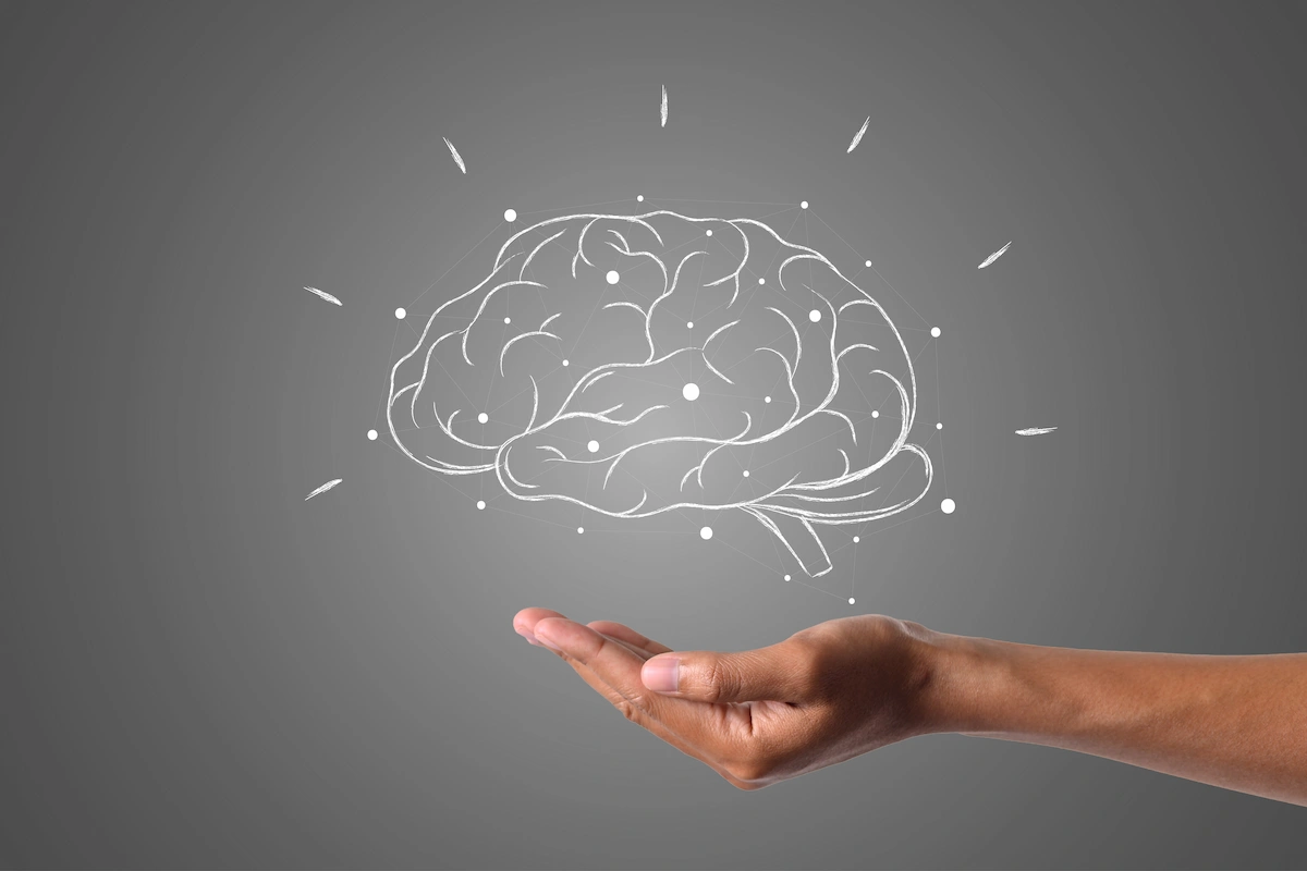 Mão segurando um cérebro ilustrado com linhas de energia, logotipo da NeuronUP sobre fundo neutro.
