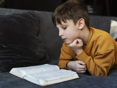 Lehrreiche Illustration eines Kindes, das auf einem Sofa ein Buch liest; Thema: Koexistenz von Autismus und Dyslexie.