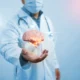 Ärztin oder Arzt im weißen Kittel und mit Maske hält eine beleuchtete dreidimensionale Darstellung eines Gehirns vor einem klinischen oder technologischen Hintergrund.