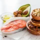 Zusammenstellung gesunder Lebensmittel: Lachs, Avocado, Olivenöl und Nüsse zur Veranschaulichung von Omega-3 und Aufmerksamkeit.