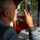 Älterer Mann im Anzug hält in einem eleganten Umfeld ein Weinglas und veranschaulicht die Neuropsychologie des Alkohols.