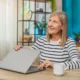 Erwachsene Frau sitzt in heller Umgebung mit Tasse und Pflanze an einem Laptop; Sprachtherapie bei Aphasie per Teletherapie.