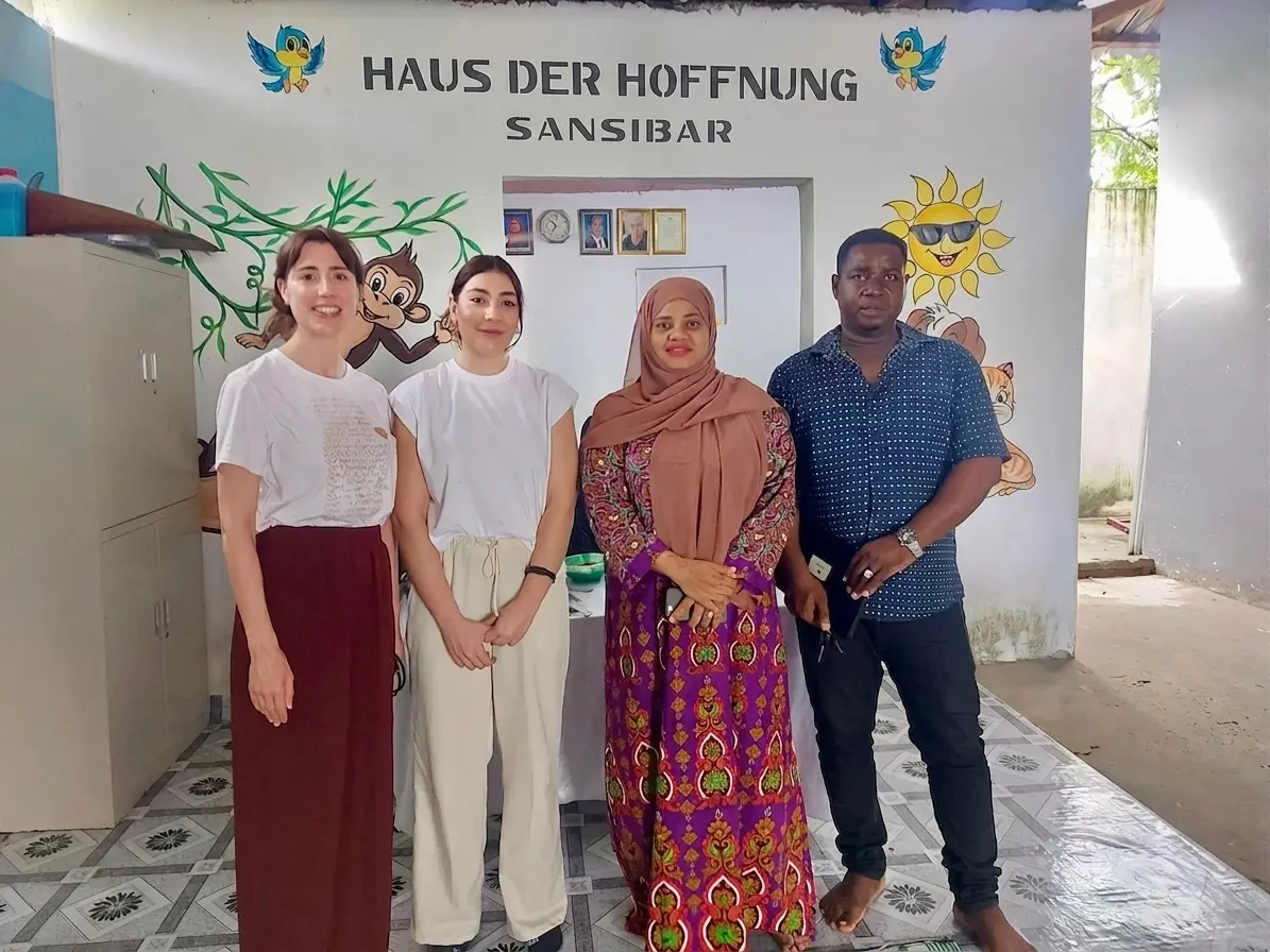 Carolina Sastre und Marina Valdevira posieren gemeinsam mit zwei Kolleginnen während einer Sitzung des NeuronUP-Teams im House of Hope auf Sansibar im Stehen.